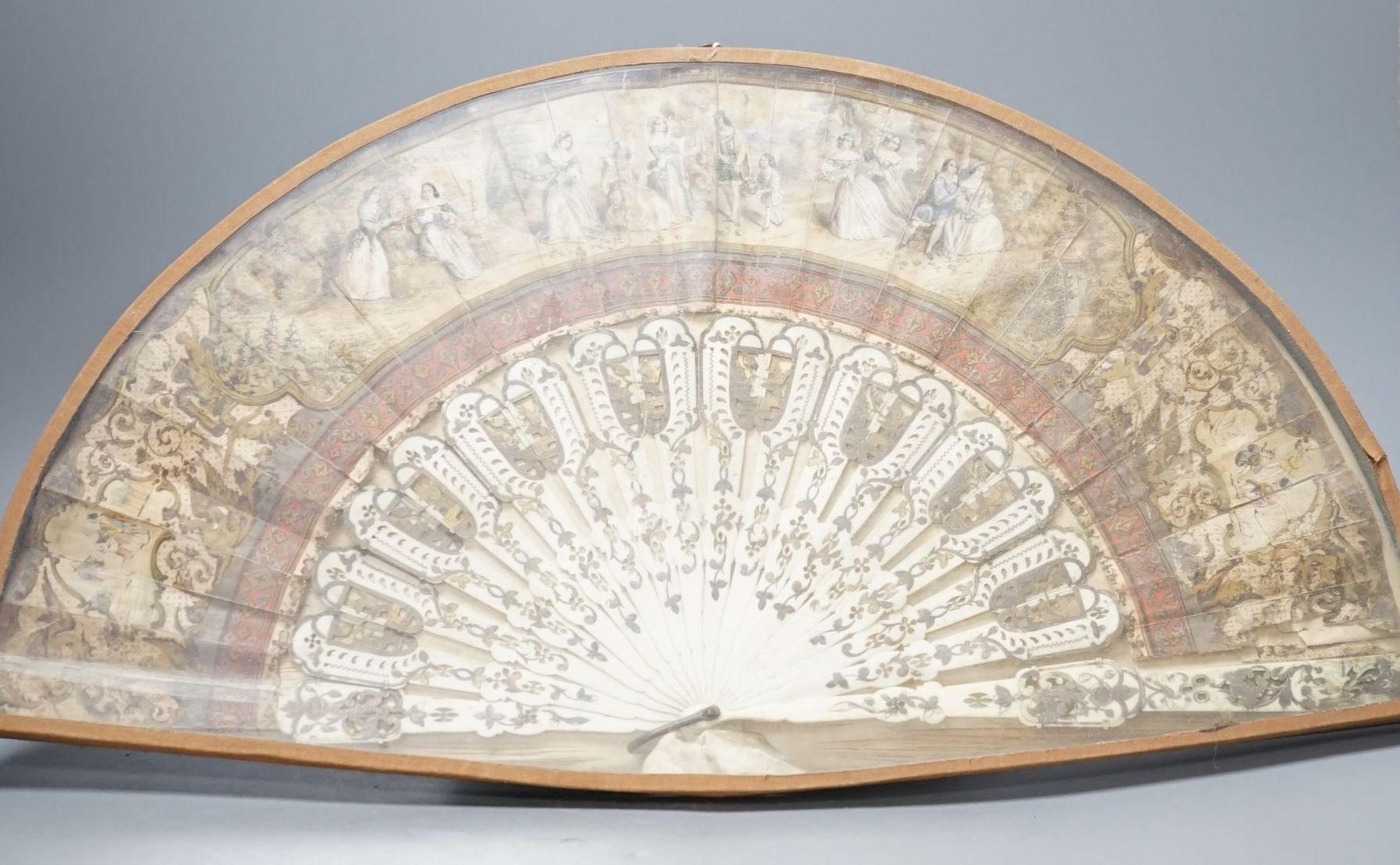 A cased 19th century French lithograph paper leaf and bone stick fan, 56 cms wide.